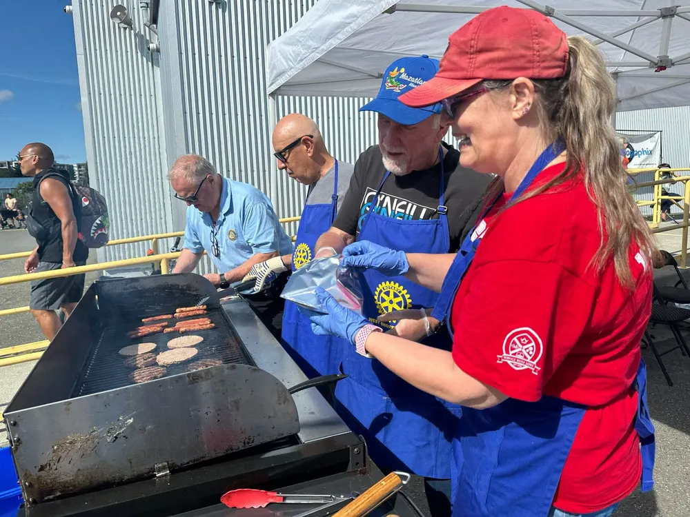 Members cooking hot dogs and burgers at a community BBQ