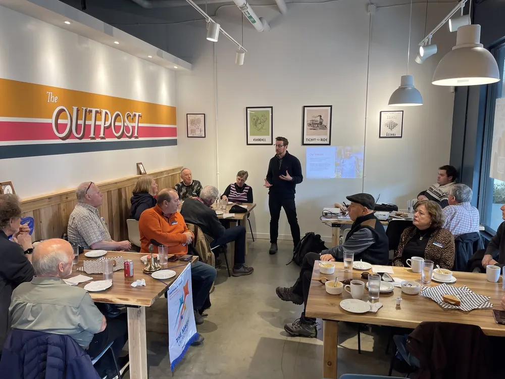 Members around tables listening to a guest speaker at a club meeting